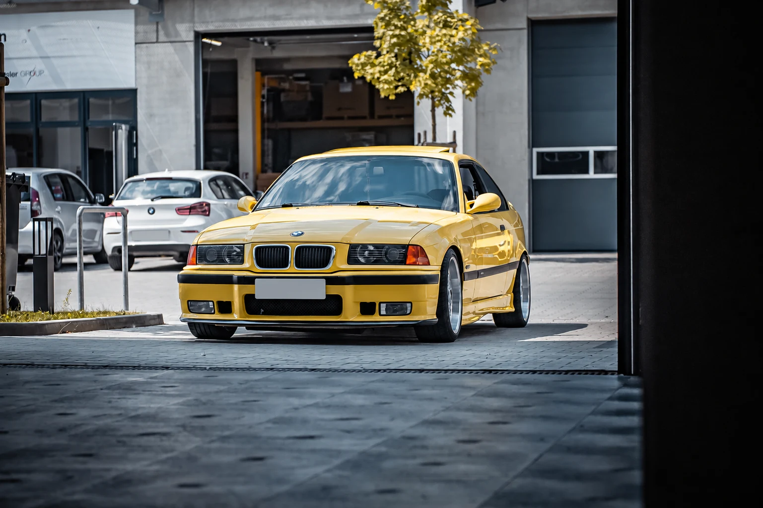 Gelber BMW E36 M3 vor der Werkstatt, Kennzeichen unkenntlich gemacht