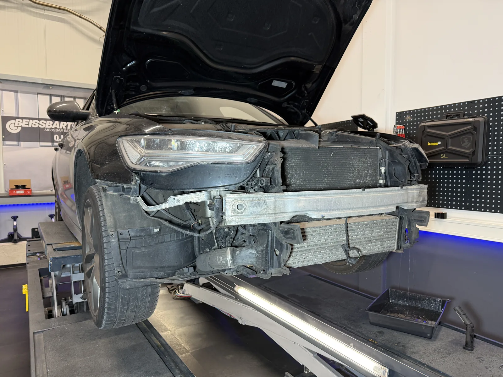 Audi auf der Hebebühne mit demontierter Frontverkleidung und sichtbarem Querträger sowie Kühlerpaket