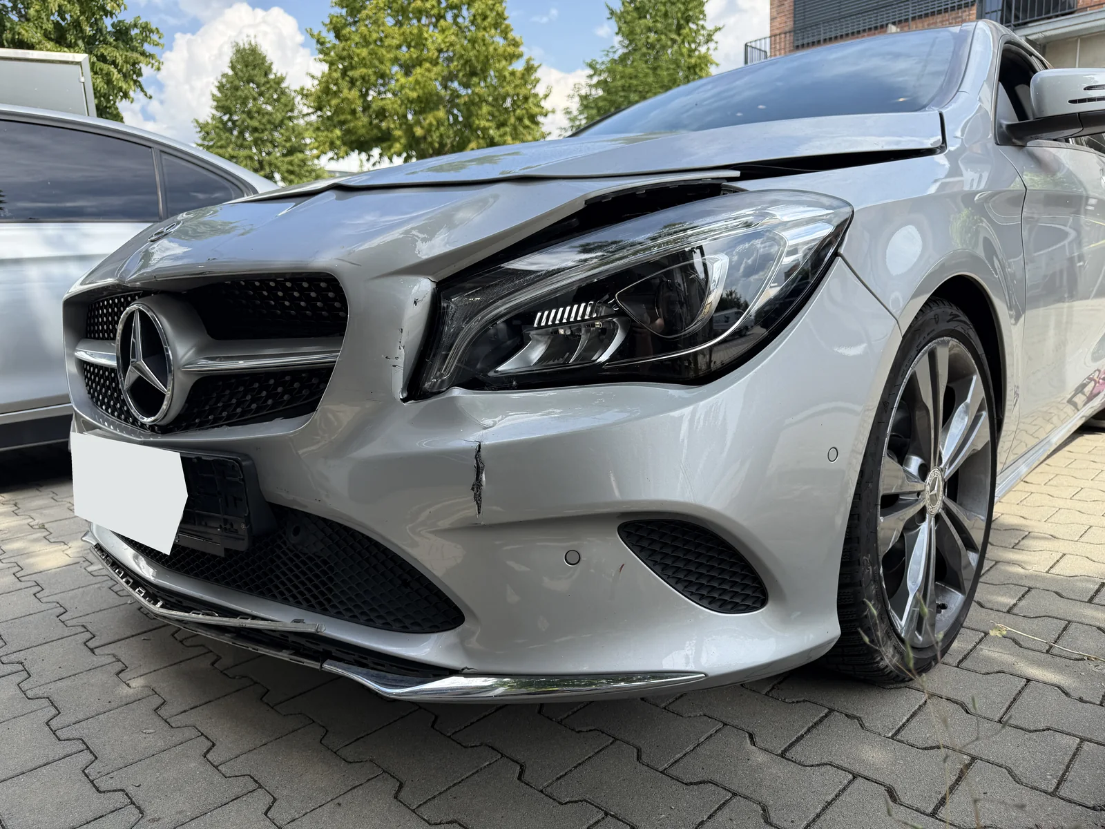 Beschädigte Front des Mercedes mit verformter Motorhaube und gerissener Stoßfängerverkleidung; Kennzeichen anonymisiert