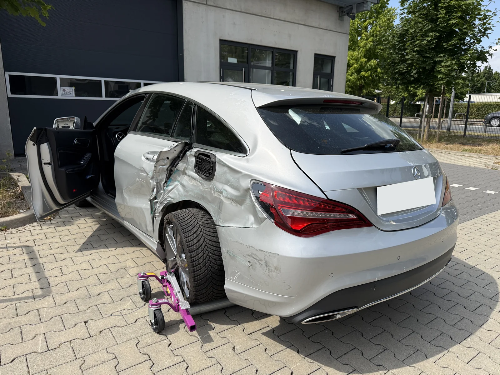 Mercedes mit stark beschädigter linker hinterer Tür und Seitenwand sowie auffälliger Radstellung; Kennzeichen anonymisiert