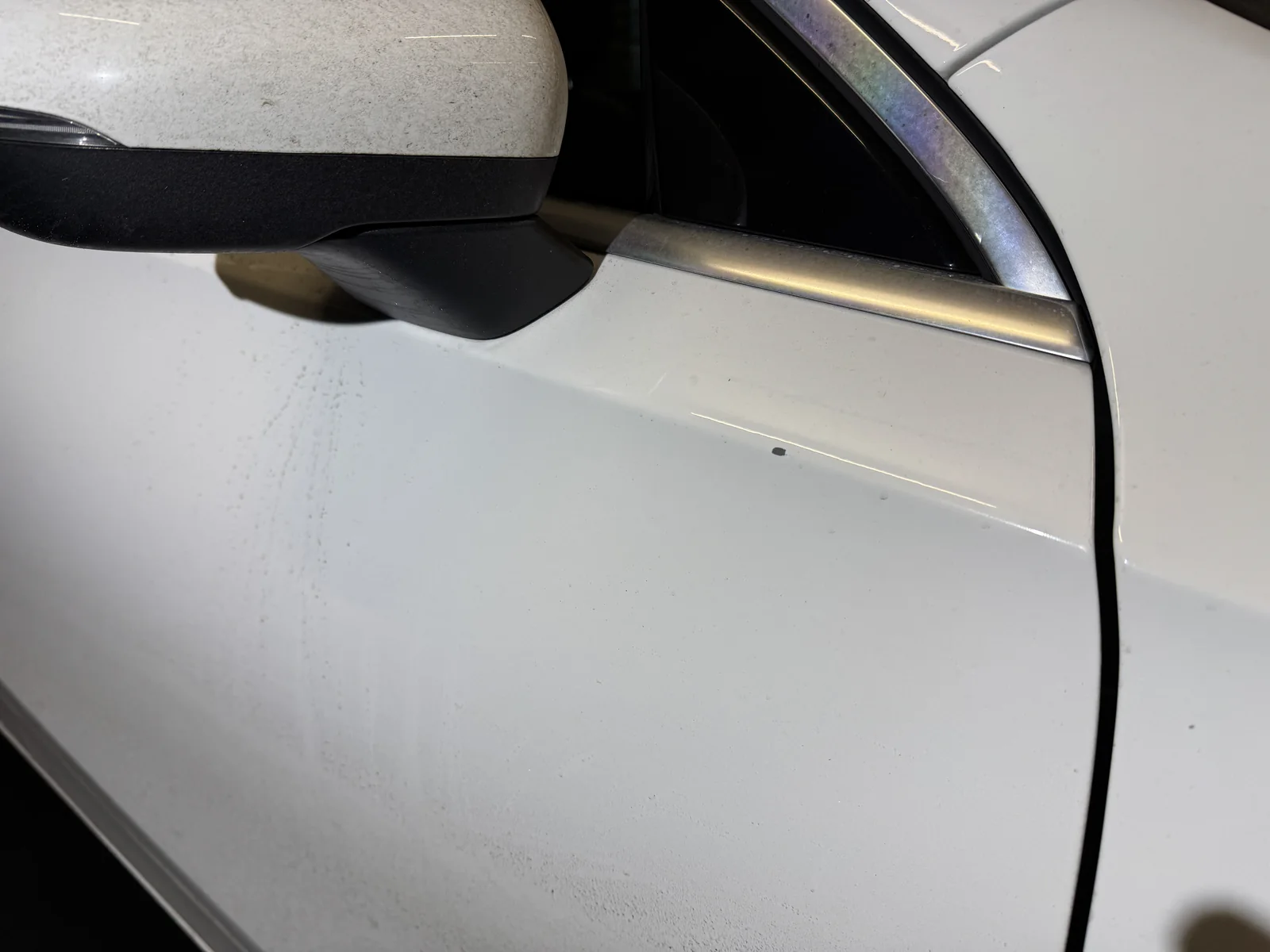 Übersicht der weißen Fahrzeugtür mit kleiner dunkler Schadenstelle unterhalb des Außenspiegels